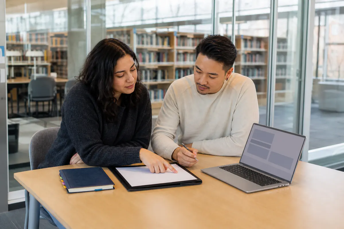 Unmarried Canadian couple preparing cohabitation agreement questions in a public library study room